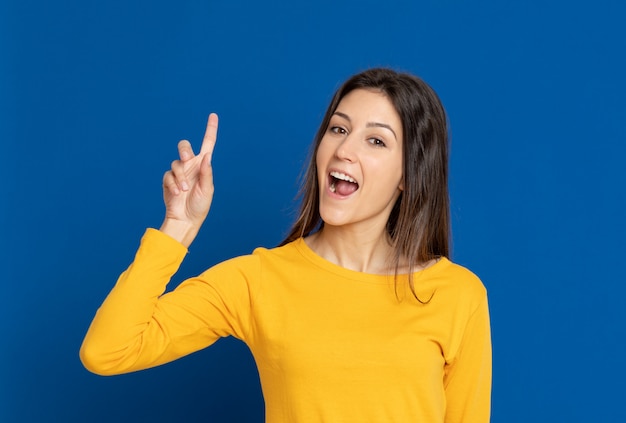 Mujer joven morena que gesticula sobre la pared azul