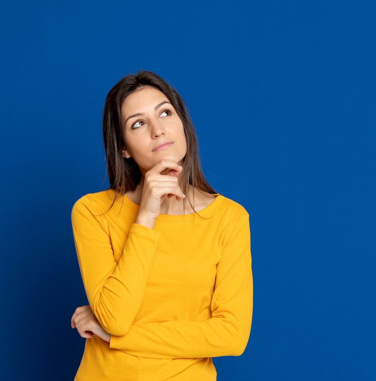Foto mujer joven morena que gesticula sobre la pared azul