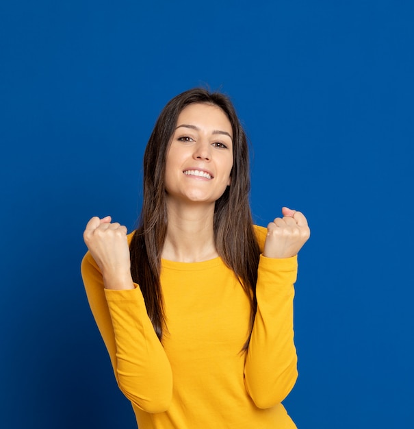 Mujer joven morena que gesticula sobre la pared azul