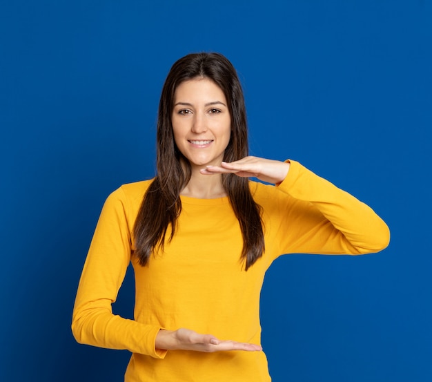 Mujer joven morena que gesticula sobre la pared azul