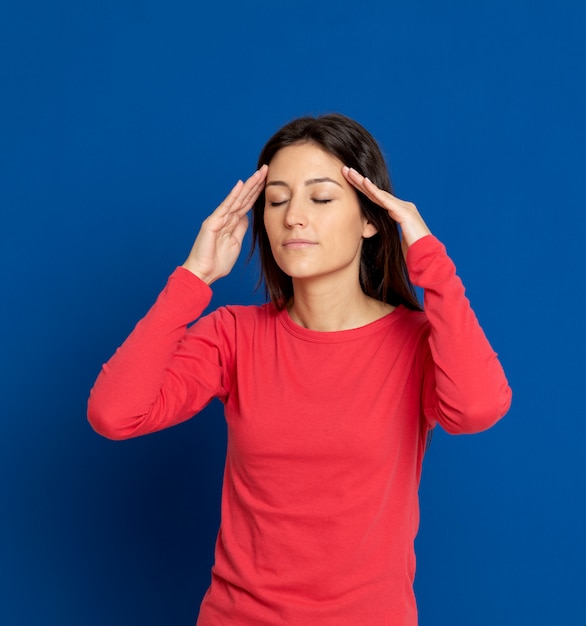 Mujer joven morena que gesticula sobre la pared azul