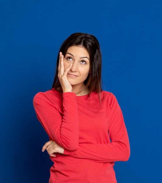 Mujer joven morena que gesticula sobre la pared azul