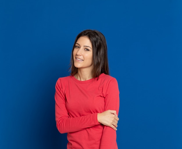 Mujer joven morena que gesticula sobre la pared azul