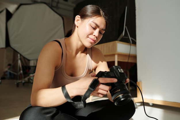 Mujer joven morena en ropa informal mirando a través de fotos de modelo de moda