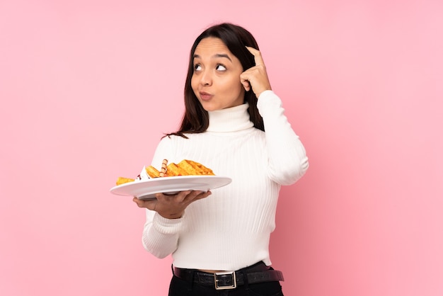 Mujer joven morena sosteniendo gofres aislado