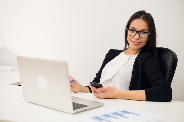 Foto mujer joven morena con un teléfono en el trabajo