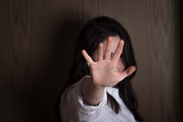 Mujer joven mostrando la mano mientras está de pie contra una pared de madera