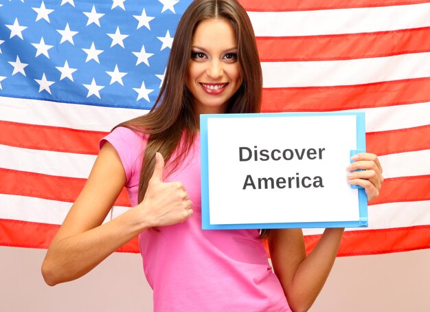 mujer joven, mujer joven, tenencia, tableta, en, plano de fondo, de, bandera americana