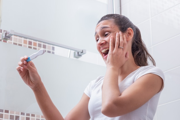 Foto mujer joven, muy contenta con el resultado de la prueba de embarazo.