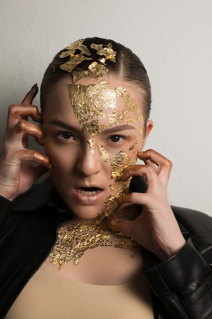 Mujer joven muy emocional con lámina de oro en la cara, el cabello y el cuello