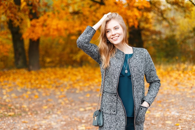 Mujer joven muy hermosa alegre con abrigo gris de moda