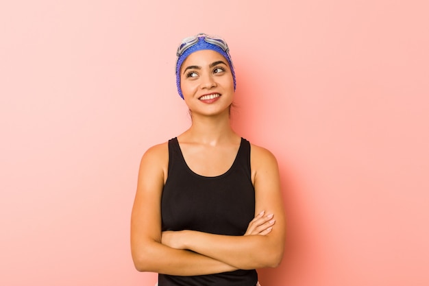 Mujer joven nadador árabe aislada sonriendo confiada con los brazos cruzados.