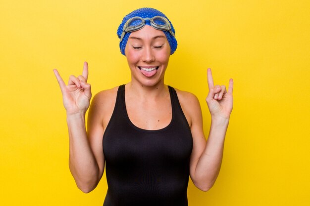 Foto mujer joven nadador australiano aislada sobre fondo amarillo mostrando gesto de rock con los dedos