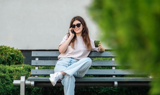 Mujer joven de negocios se sienta en un banco y habla por teléfono