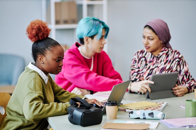 Mujer joven negra que usa una computadora portátil durante una reunión en la oficina