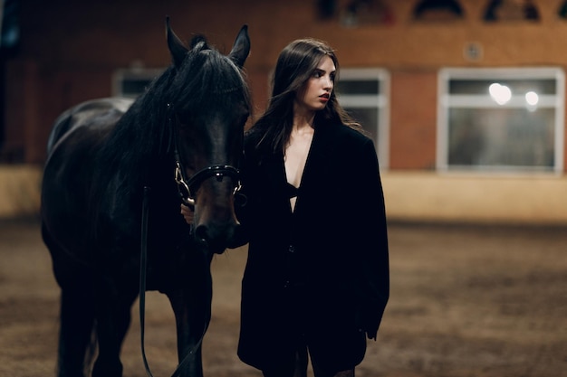 Mujer joven de negro con su caballo en el interior