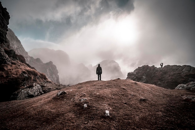 Una mujer joven en la niebla al amanecer en la cima de la montaña de Aiako Harriak