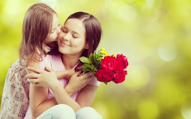 Foto mujer joven con niña y hermosas flores al aire libre