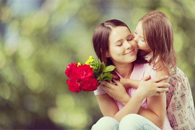 Mujer joven con niña y hermosas flores al aire libre