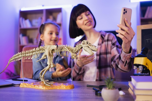 Foto mujer joven y niña linda filmando un video de su investigación científica