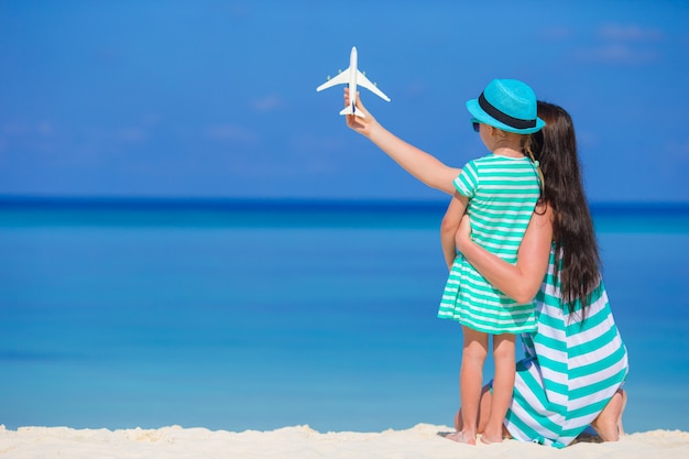 Mujer joven y niña con miniatura de avión en la playa