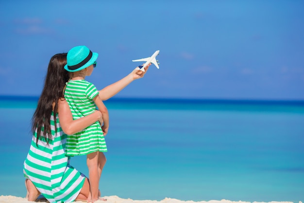 Mujer joven y niña con miniatura de avión en la playa