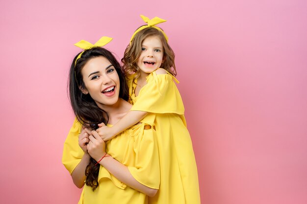 Mujer joven con niño lindo posando en vestidos amarillos