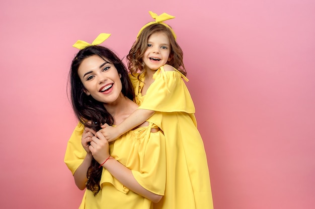 Mujer joven con niño lindo posando en vestidos amarillos