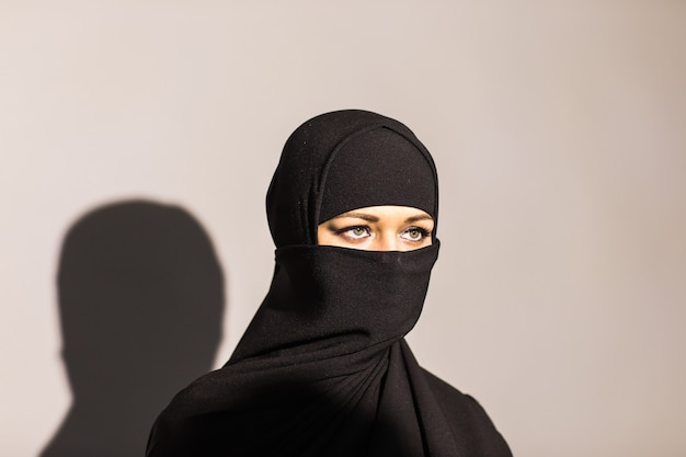 Mujer joven con niqab negro sobre fondo.