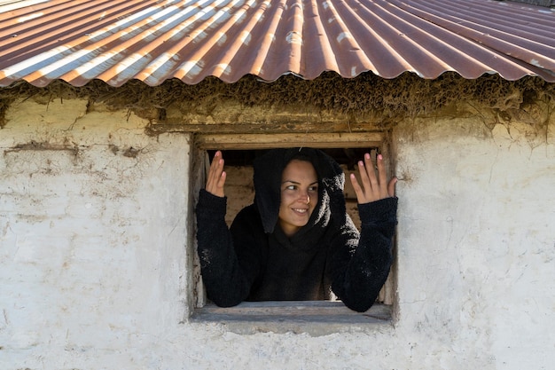 Una mujer joven observa detrás de la ventana.