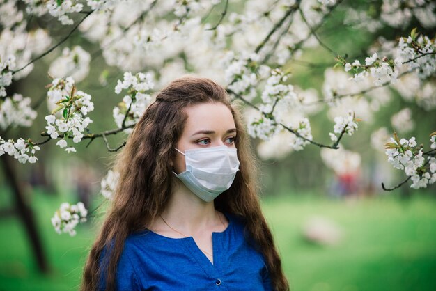 Mujer joven de ojos azules con máscara en el parque de la flor