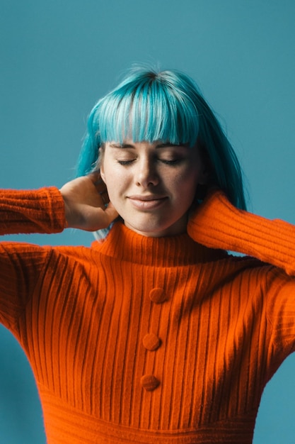 Foto mujer joven con los ojos cerrados contra el fondo azul.