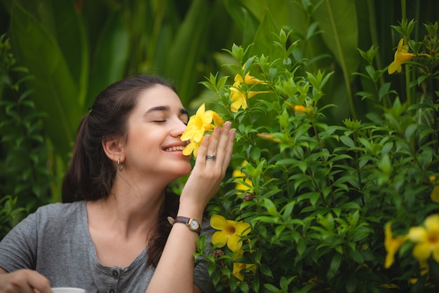 Mujer joven, oler, flores amarillas