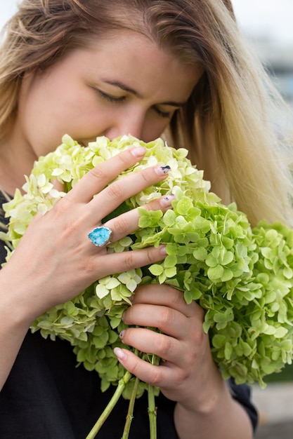 Mujer joven oliendo un ramo de hortensias