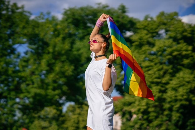 Mujer joven ondeando la bandera del orgullo LGBT en el parque