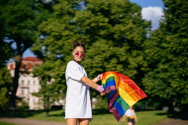 Mujer joven ondeando la bandera del orgullo LGBT en el parque