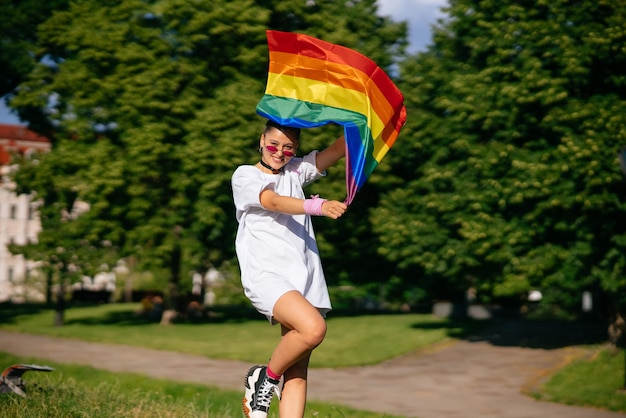 Mujer joven ondeando la bandera del orgullo LGBT en el parque