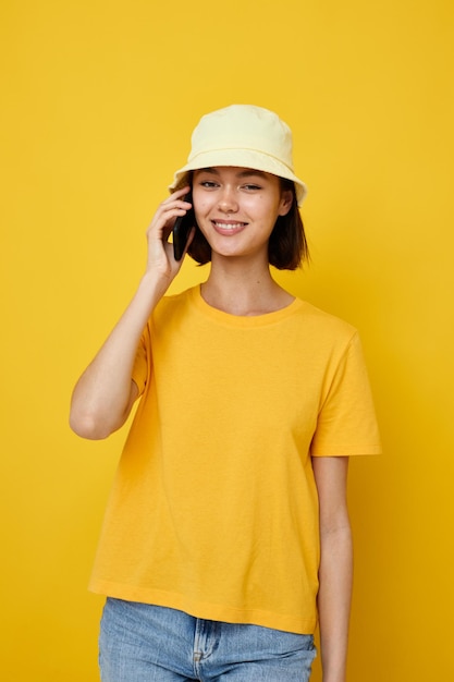 Mujer joven optimista en un sombrero amarillo estilo juvenil casual hablando por teléfono estilo de vida inalterado