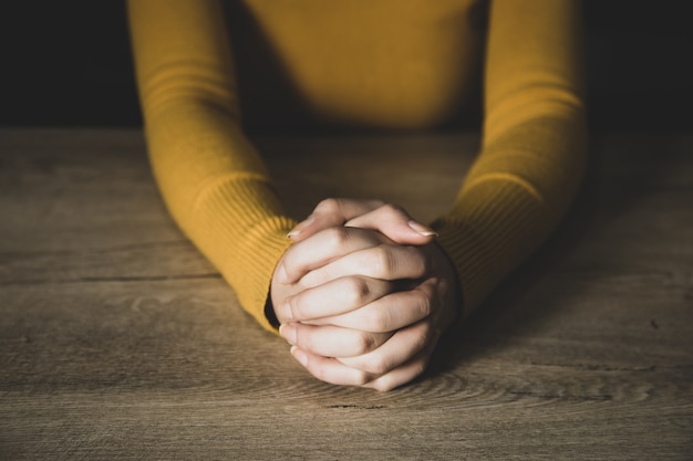 Mujer joven de oración en una habitación oscura