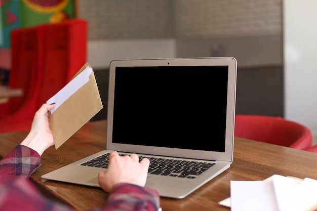 Mujer joven con ordenador portátil y correo en la mesa de café