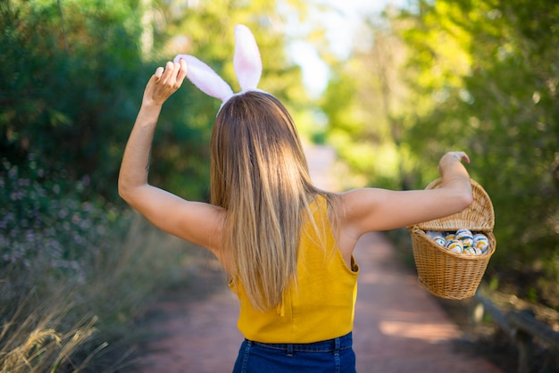 Mujer joven con orejas de conejo y con coloridos huevos de Pascua al aire libre