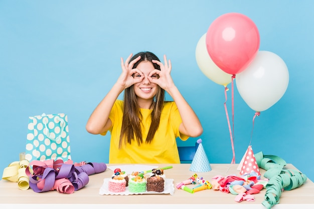 Mujer joven organizando un cumpleaños que muestra bien firmar sobre los ojos