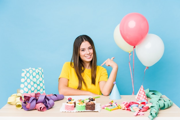 Mujer joven organizando una persona de cumpleaños señalando con la mano a una camisa copia espacio, orgullosa y segura