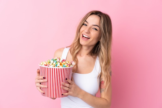 Mujer joven con palomitas de maíz sobre pared aislada