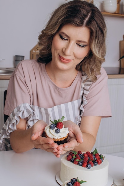 Mujer joven panadera sosteniendo cupcakes