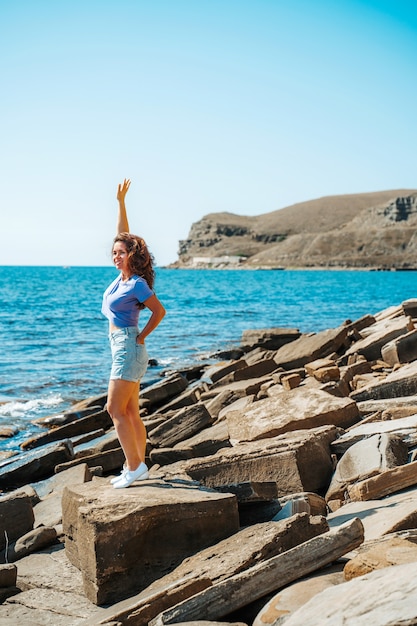 Una mujer joven en pantalones cortos en una playa rocosa de piedras naturales en Crimea