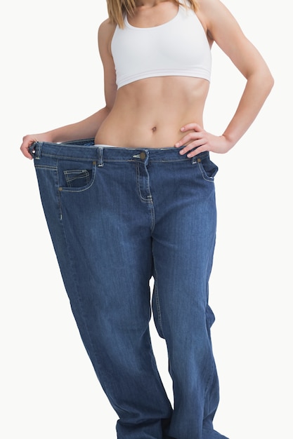 Mujer joven con pantalones viejos después de perder peso