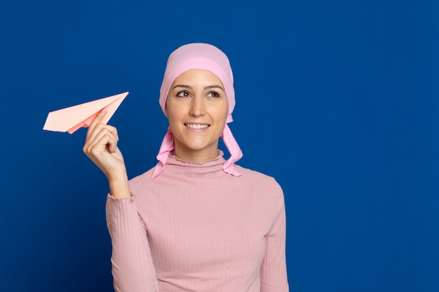 Mujer joven con pañuelo rosa en la cabeza sobre un azul