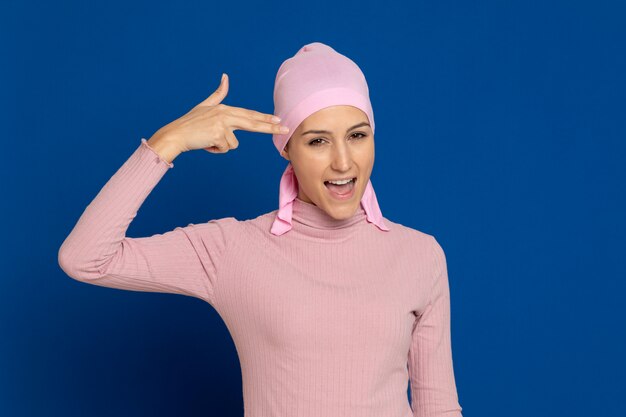 Mujer joven con pañuelo rosa en la cabeza sobre un azul