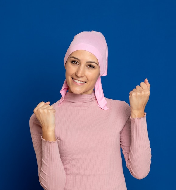 Mujer joven con pañuelo rosa en la cabeza sobre un azul
